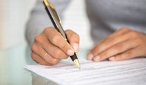 Person signing a document with a pen