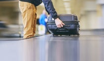 Man lifting suitcase off a baggage carousel at the airport