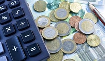 Close up of Euro coins and notes beside a calculator and a pencil