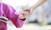 Carer holding hand of person needing assistance