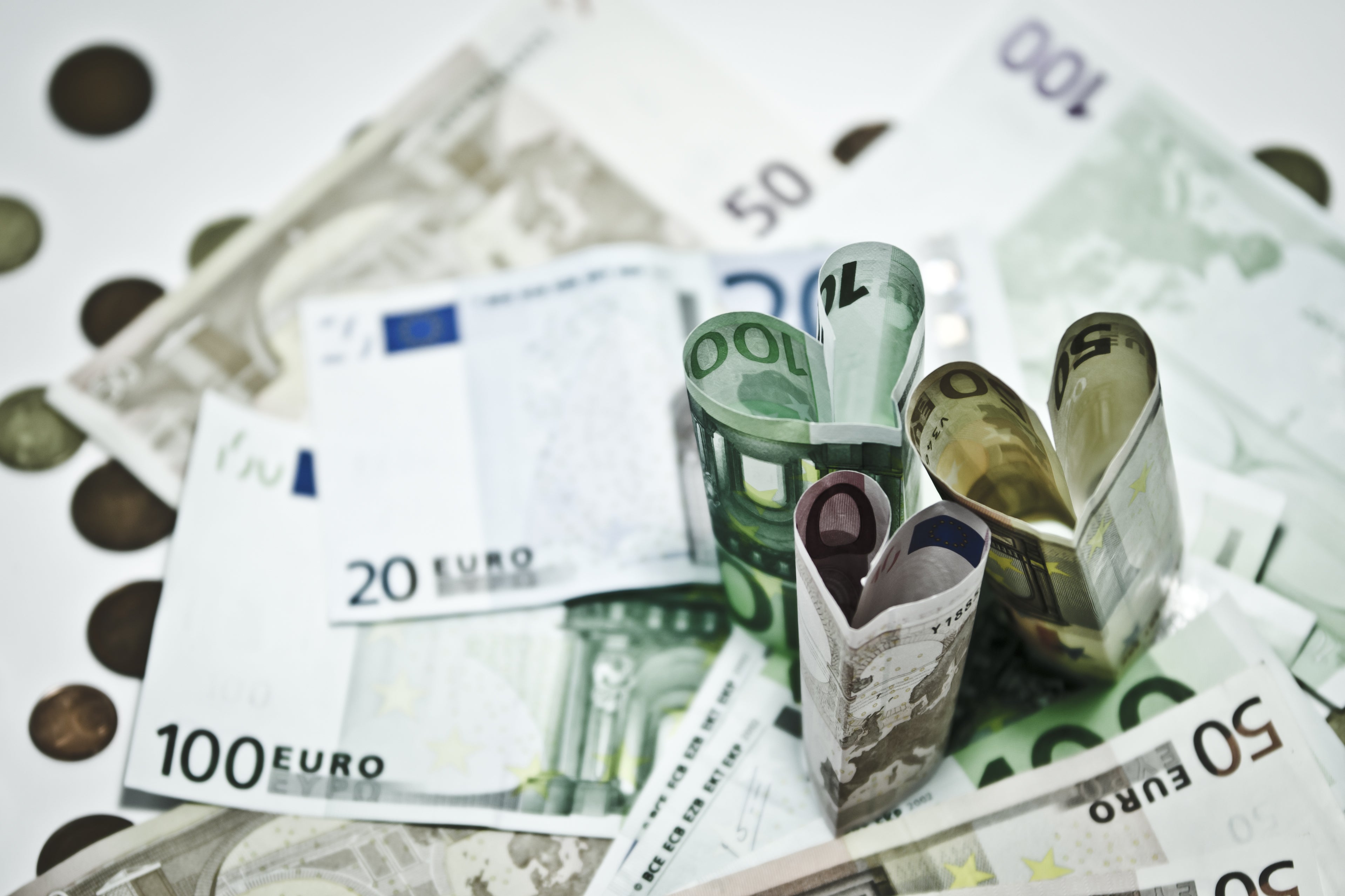 Euro currency notes on a table with three notes upstanding and folded into heart shapes