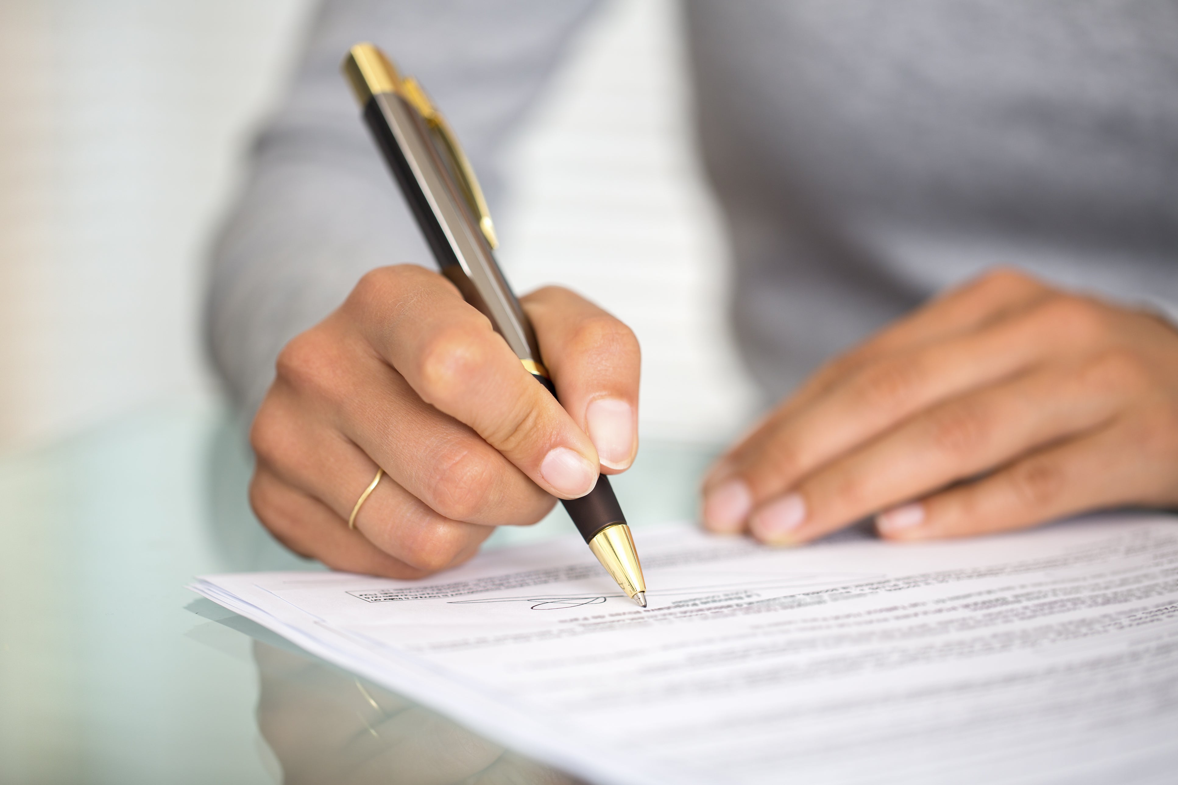 Person signing a document with a pen