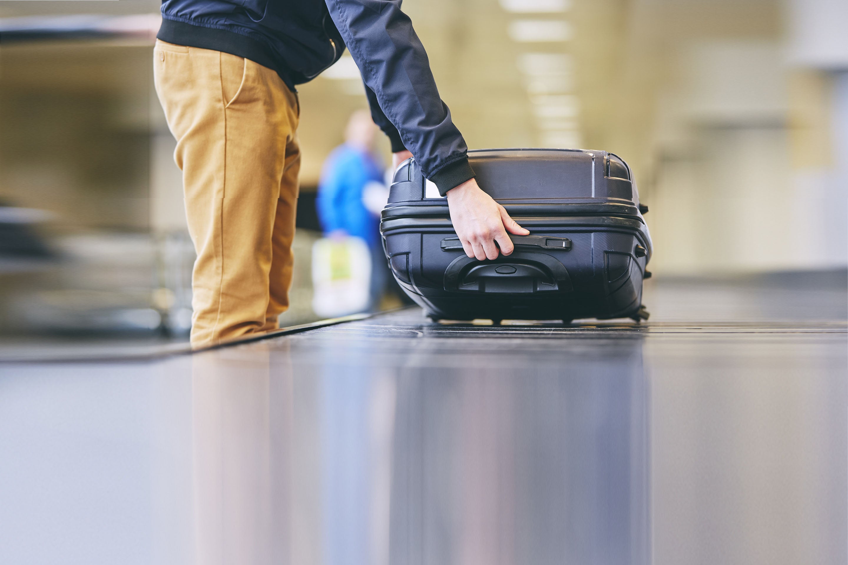 Man lifting suitcase off a baggage carousel at the airport