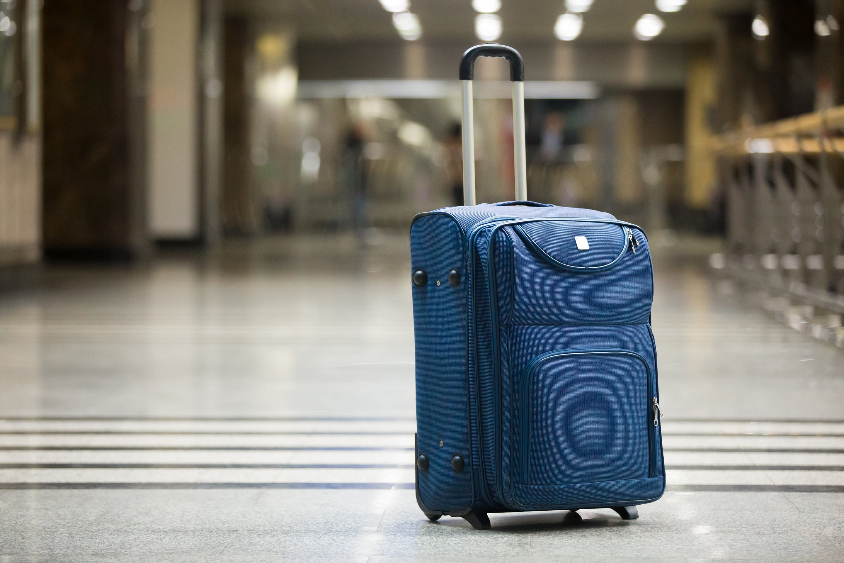 Blue upright standing suitcase at the airport