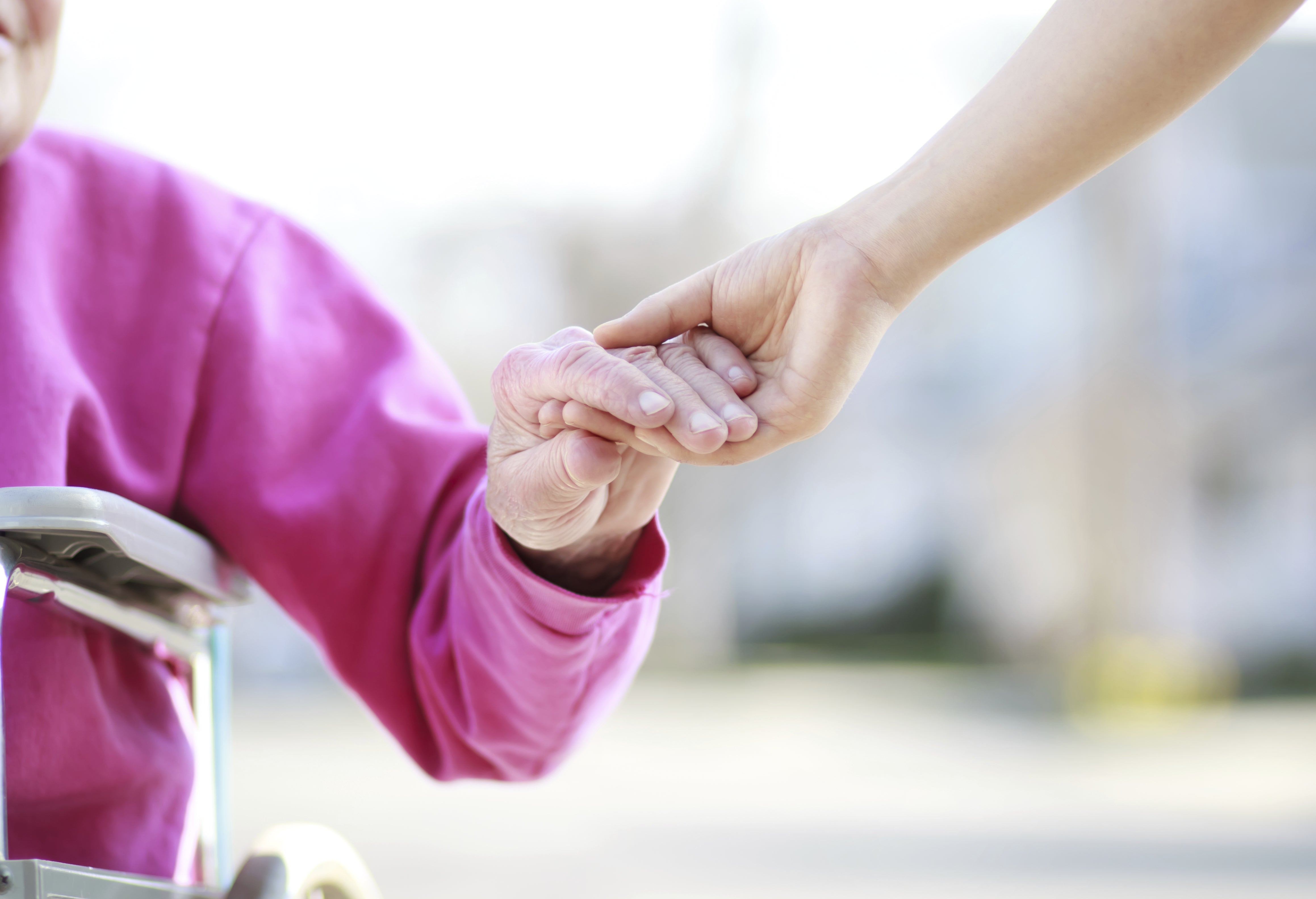 Carer holding hand of person needing assistance